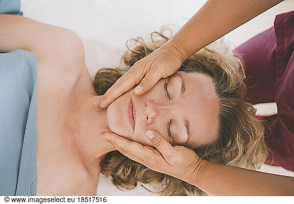Therapist giving facial massage to customer in salon