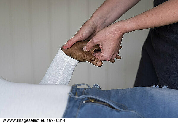 Therapist touching a client's hands.