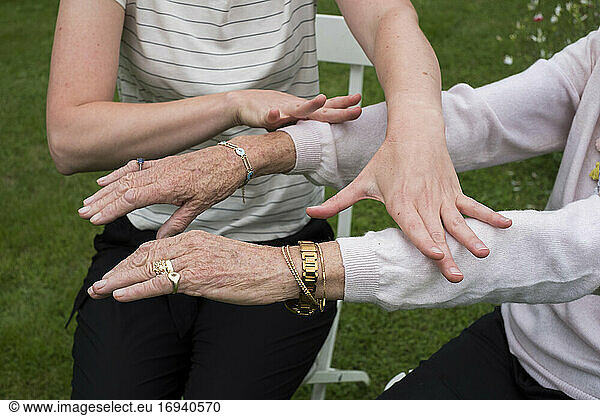 Therapist touching the outstretched arms of her client.