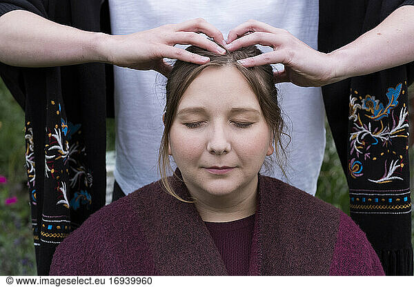 Therapist using both hands touching the top of a client's head.