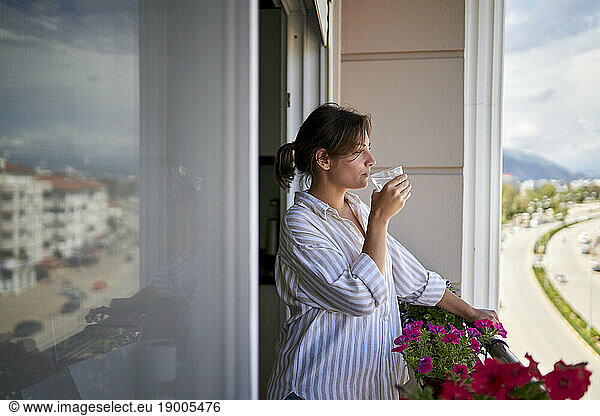 Thirsty woman drinking water in balcony