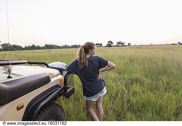 Thirteen year old girl leaning on safari vehicle  Botswana