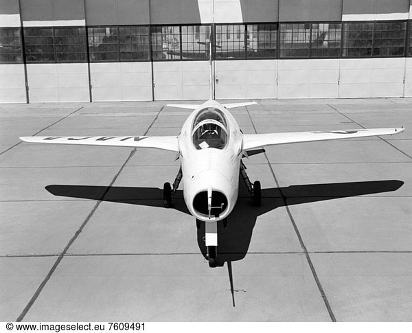 This NACA High_Speed Flight Research Station photograph of the X_5 was taken at the South Base of Edwards Air Force Base. The photograph shows a frontal view of the X_5 on the ramp in_front of the NACA hangar. This view also provides a good view of the pitot_static probe  used to measure airspeed  Mach number  and altitude  mounted on a nose boom protruding from the top of the aircraft´s nose engine inlet. Also attached to the pitot_static probe portion of the nose boom are flow direction vanes for sensing the aircraft´s angles_of_attack and sideslip in flight.