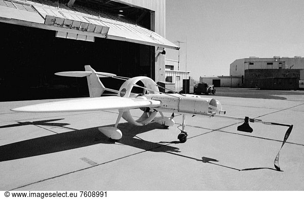 This 1976 photograph of the Oblique Wing Research Aircraft was taken in front of the NASA Flight Research Center hangar  located at Edwards Air Force Base  California. In the photograph the noseboom  pitot_static probe  and angles_of_attack and sideslip flow vanescovered_up are attached to the front of the vehicle. The clear nose dome for the television camera  and the shrouded propellor for the 90 horsepower engine are clearly seen. The Oblique Wing Research Aircraft was a small  remotely piloted  research craft designed and flight tested to look at the aerodynamic characteristics of an oblique wing and the control laws necessary to achieve acceptable handling qualities. NASA Dryden Flight Research Center and the NASA Ames Research Center conducted research with this aircraft in the mid_1970s to investigate the feasibility of flying an oblique wing aircraft.