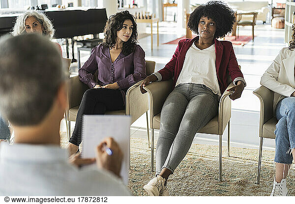 Thoughtful Afro businesswoman sharing ideas with colleagues in brainstorming session at office