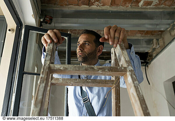Thoughtful architect at step ladder in a house under construction