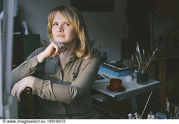 Thoughtful artist with hand on chin in studio