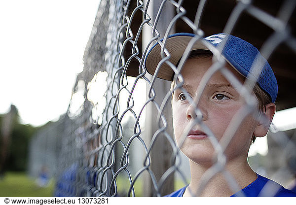 Thoughtful boy looking away while standing in dugout