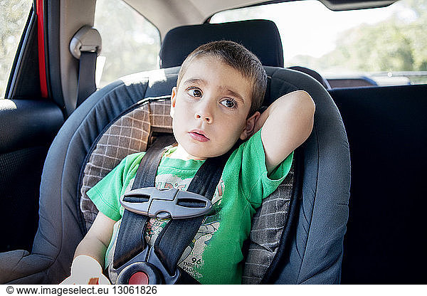 Thoughtful boy sitting in car seat