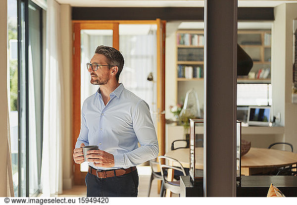 Thoughtful businessman drinking coffee at home