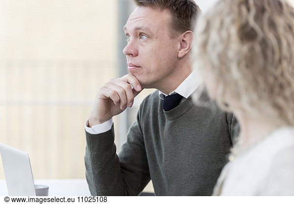 Thoughtful businessman sitting with female colleague in office