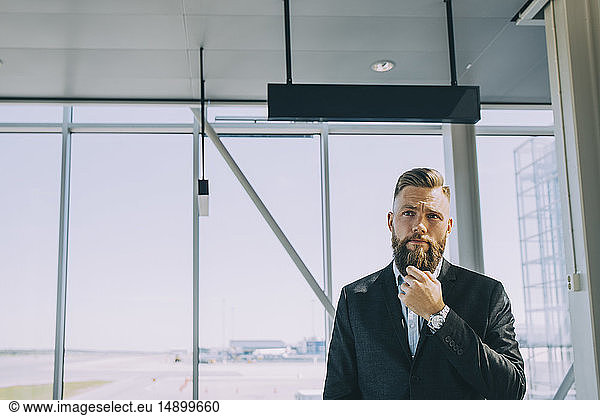 Thoughtful businessman standing against window at airport