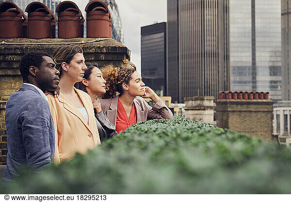 Thoughtful businessman with colleagues standing at rooftop