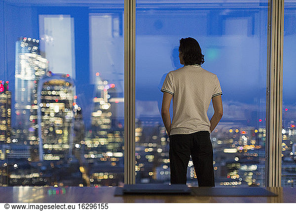 Thoughtful businessman working late at highrise window  London  UK