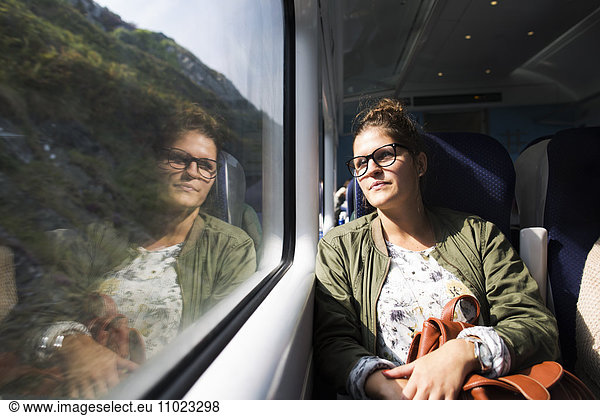 Thoughtful businesswoman looking through train window
