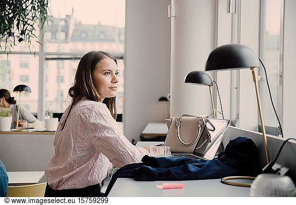 Thoughtful businesswoman sitting at desk in creative office