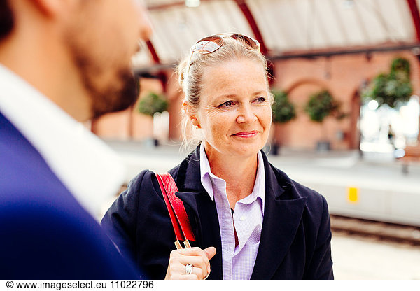 Thoughtful businesswoman standing with colleague at railroad station