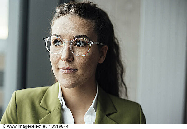 Thoughtful businesswoman wearing eyeglasses at the window