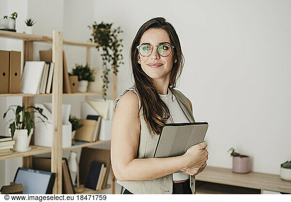 Thoughtful businesswoman wearing eyeglasses standing in office