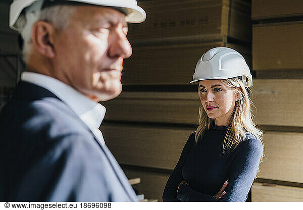 Thoughtful businesswoman wearing hardhat in carpentry factory