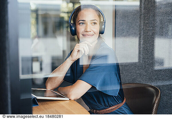 Thoughtful businesswoman wearing headset in soundproof cabin