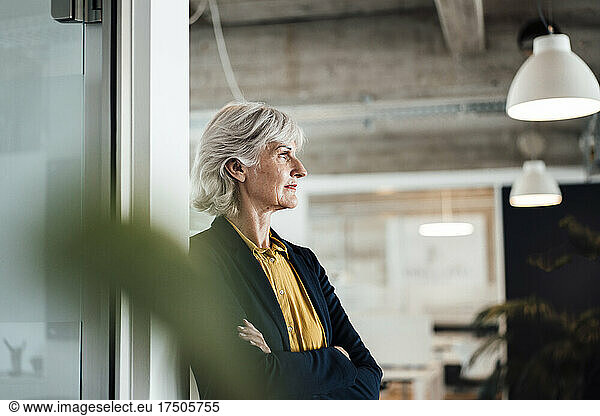 Thoughtful businesswoman with arms crossed at office