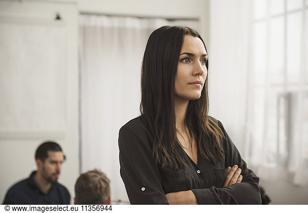 Thoughtful businesswoman with arms crossed in office