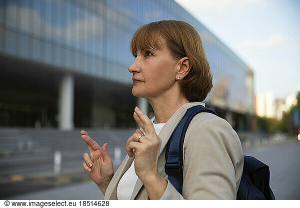Thoughtful businesswoman with crossed fingers