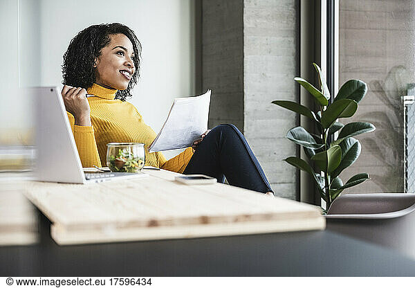 Thoughtful businesswoman with document in office