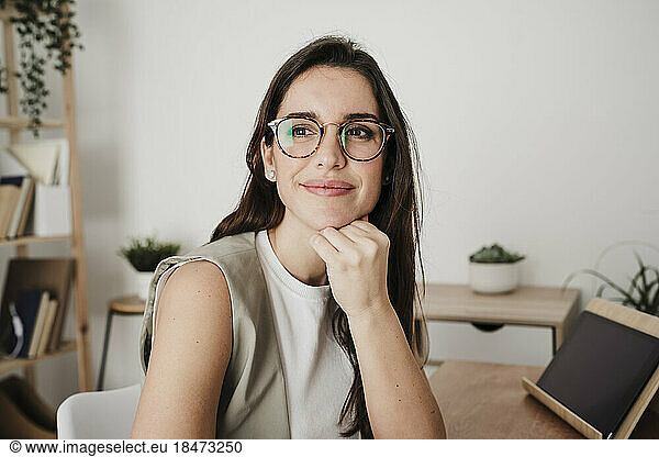 Thoughtful businesswoman with hand on chin sitting in office