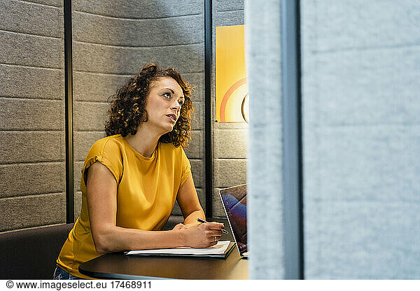 Thoughtful businesswoman with paper at desk