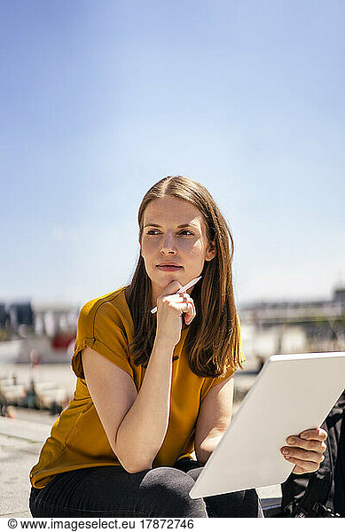 Thoughtful businesswoman with tablet PC on sunny day