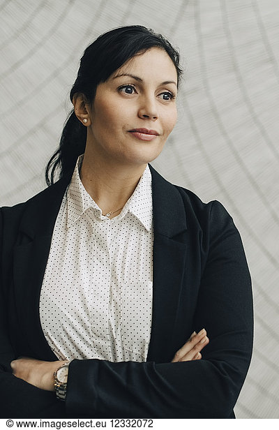 Thoughtful confidence businesswoman standing against wall at office