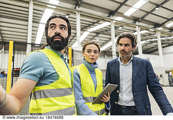 Thoughtful engineers wearing protective work wear in factory
