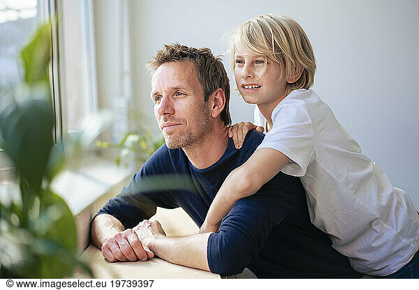 Thoughtful father and son in front of white wall at home