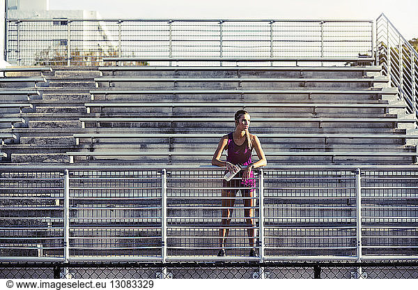Thoughtful female athlete standing on bleachers