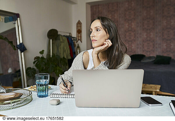 Thoughtful freelancer with laptop working at home