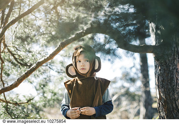 Thoughtful girl in monkey suit standing by tree at yard