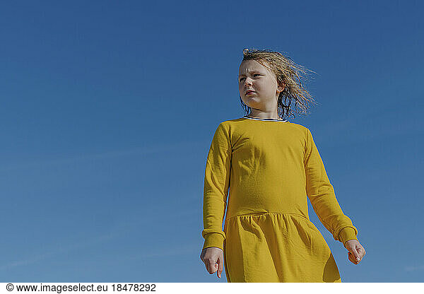 Thoughtful girl standing under blue sky with wet hair