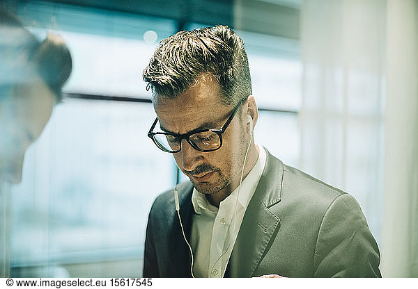 Thoughtful male professional wearing eyeglasses and headphones in office