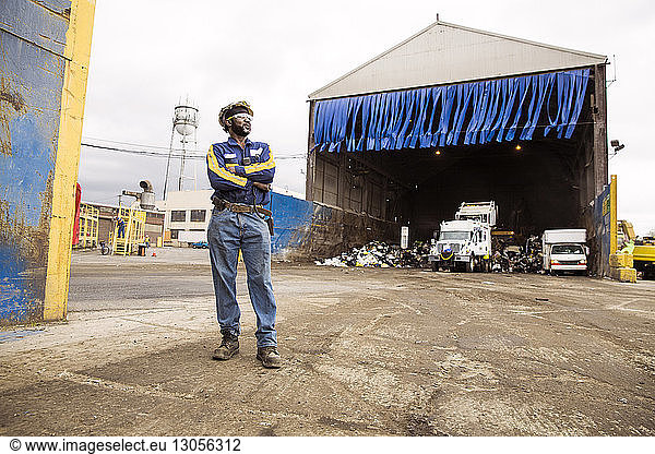 Thoughtful male worker standing against recycling plant
