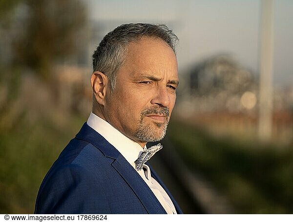 Thoughtful man in blue suit with bow tie  Rhine harbour  Karlsruhe