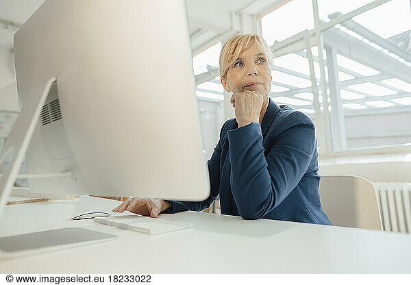 Thoughtful mature businesswoman at desk in office