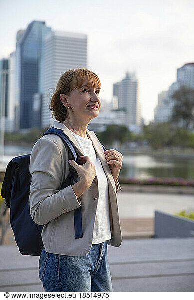 Thoughtful mature businesswoman wearing backpack