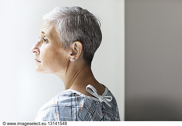 Thoughtful mature female patient standing in clinic