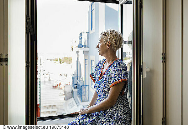 Thoughtful mature woman looking through window