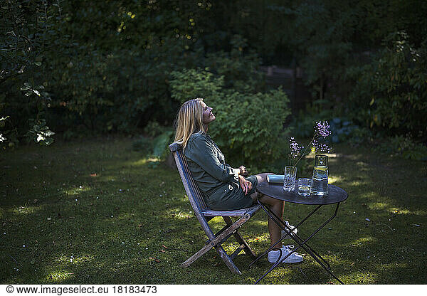 Thoughtful mature woman sitting on chair in garden