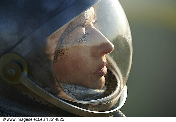 Thoughtful mature woman wearing space helmet