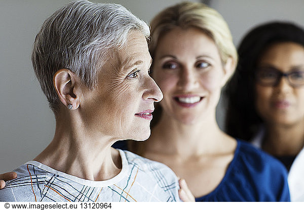 Thoughtful mature woman with daughter and doctor in background