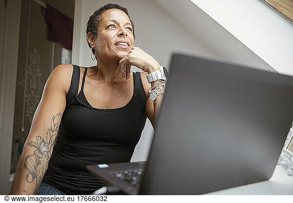 Thoughtful mature woman working from home at laptop